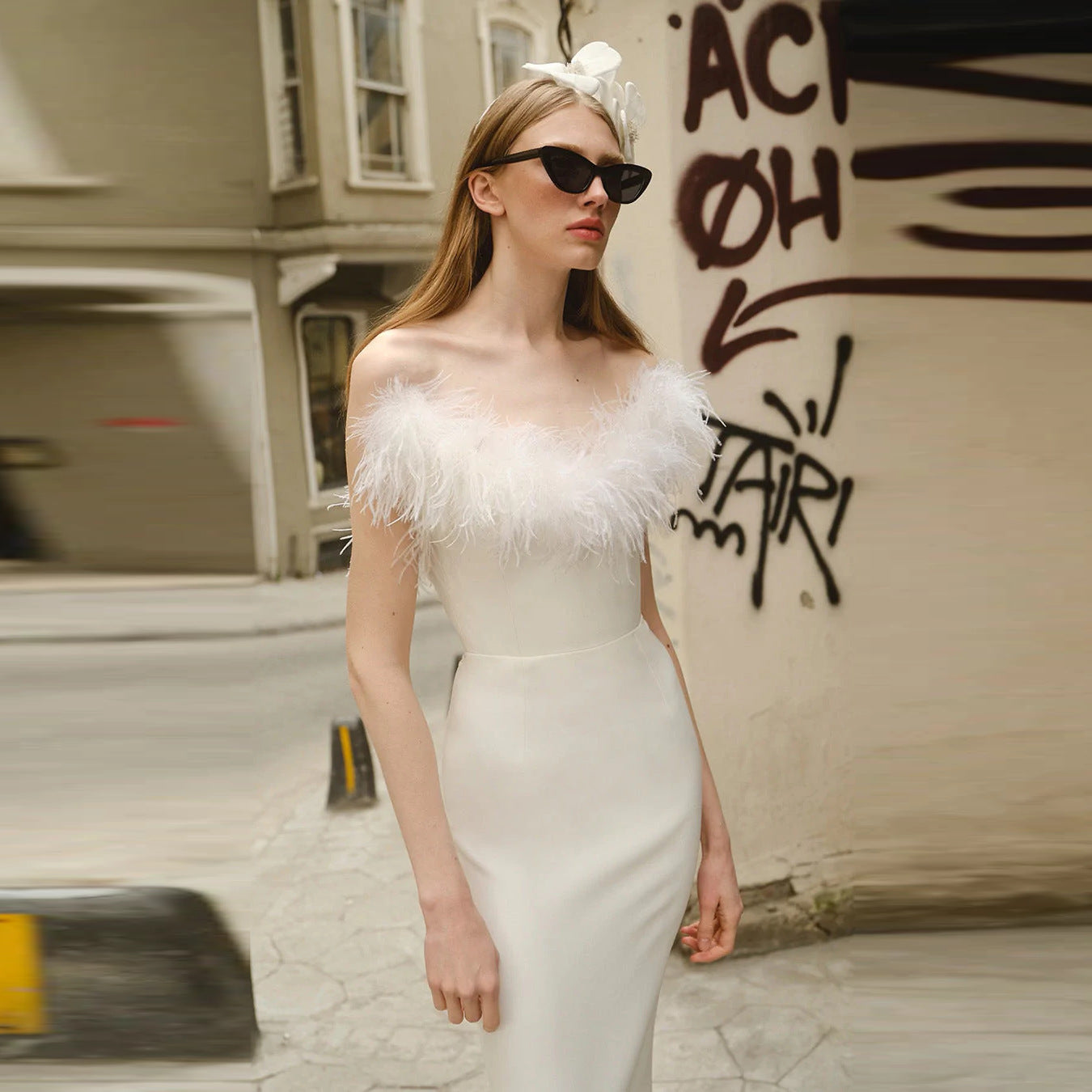 ide view of a white off-shoulder ostrich feather evening dress showcasing the form-fitting silhouette and backless design.