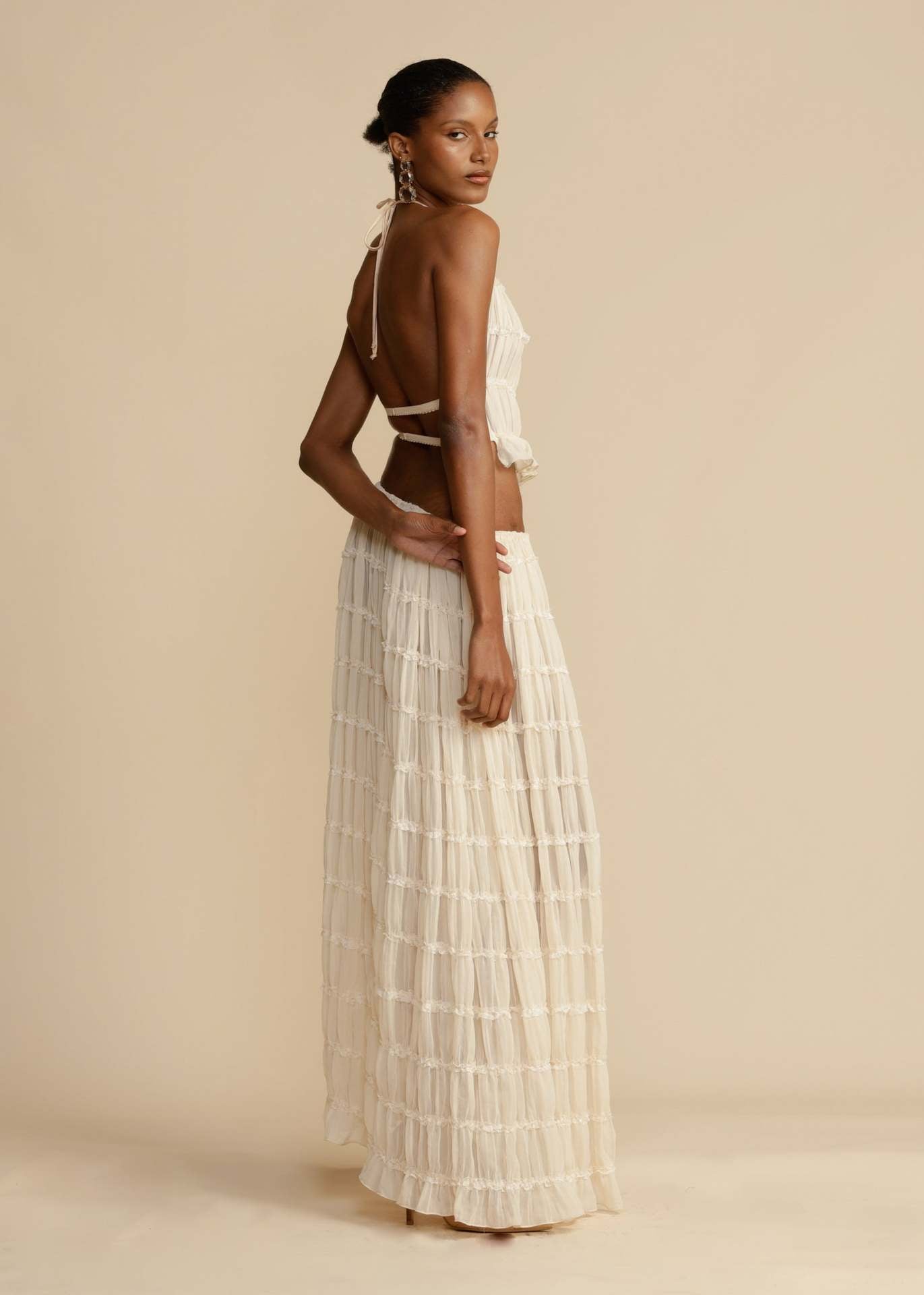 Side view of the White Chiffon Backless Lace-up Pleated Maxi Dress, highlighting the flowing pleats and flattering silhouette.