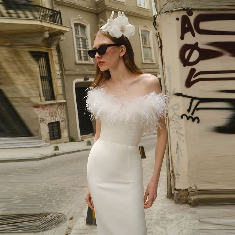Front view of a white off-shoulder ostrich feather evening dress featuring a deep V-neckline, sleeveless design, and low slit.